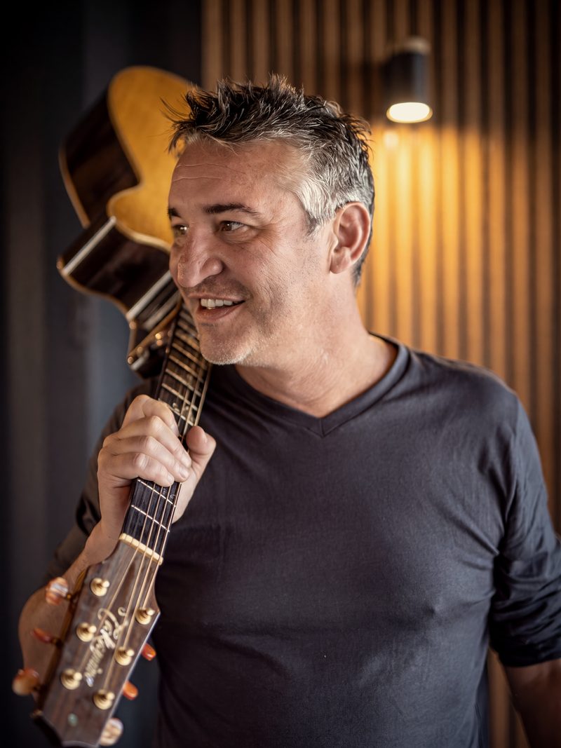 Adam Tas met kitaar oor die skouer in die studio